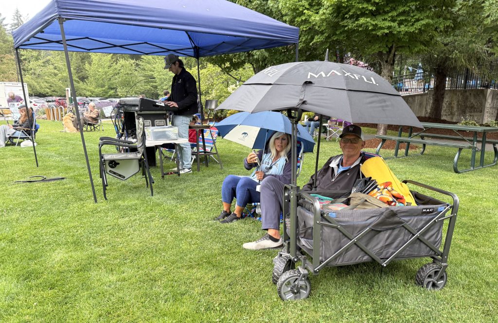 Photo of Happy listener with umbrella and cart with picnic supplies at 7/16/26 Music in the Park